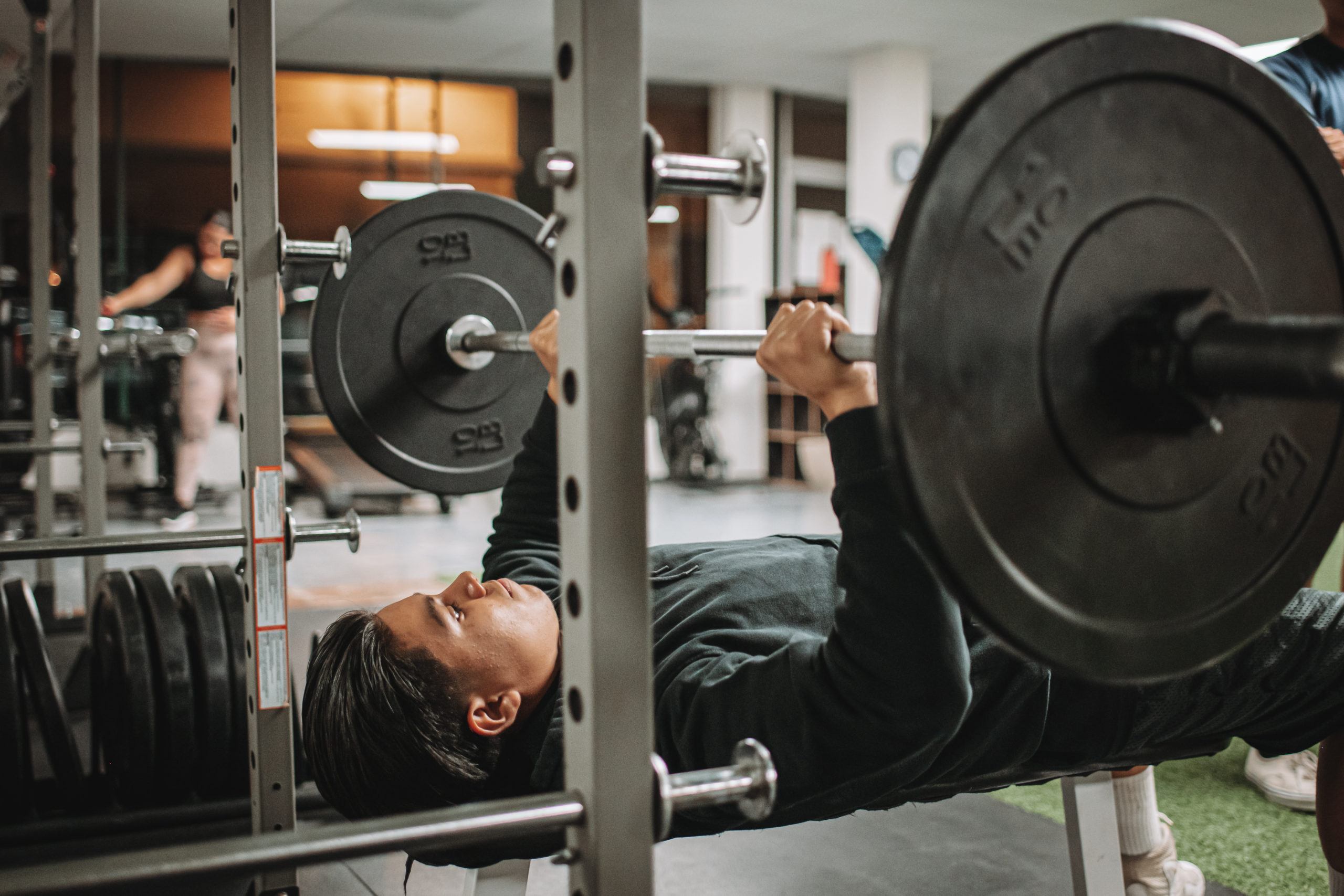 A lifter pressing a barbell on a bench at Switch Fitness San Diego.